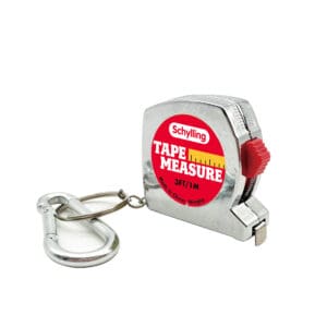 TPM_Image3 A small, silver tape measure with a carabiner attachment. The tape measure has a red and yellow label that reads "Schylling TAPE MEASURE, 3FT/1M." A metal carabiner is attached to the chain loop.