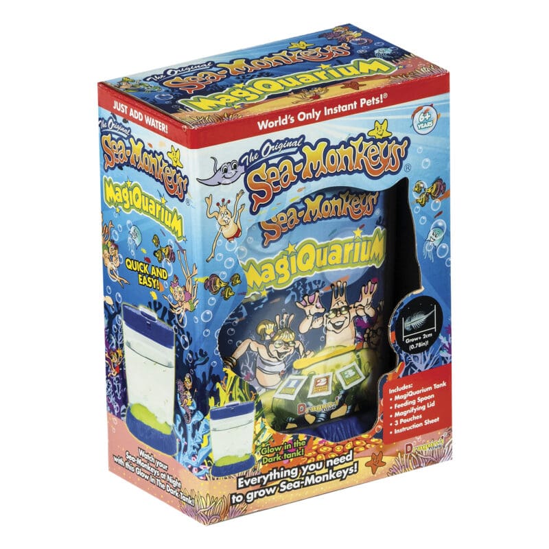 23228-Sea-Monkeys-Magiquarium-Image1 A box sitting at an angle with an opening at the front to see the covered Magiquarium inside. The product name and information is visible on the package.